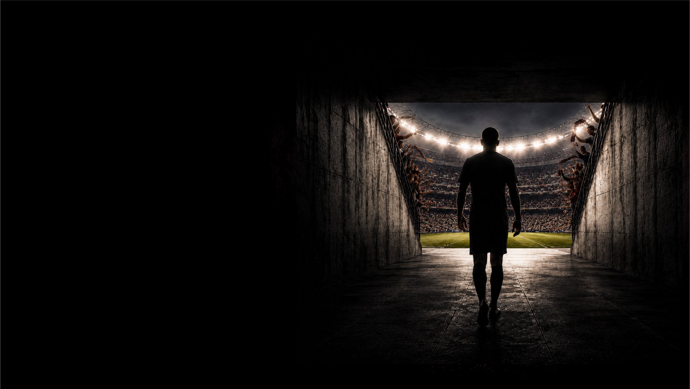 A footballer walking through a stadium tunnel toward the pitch.